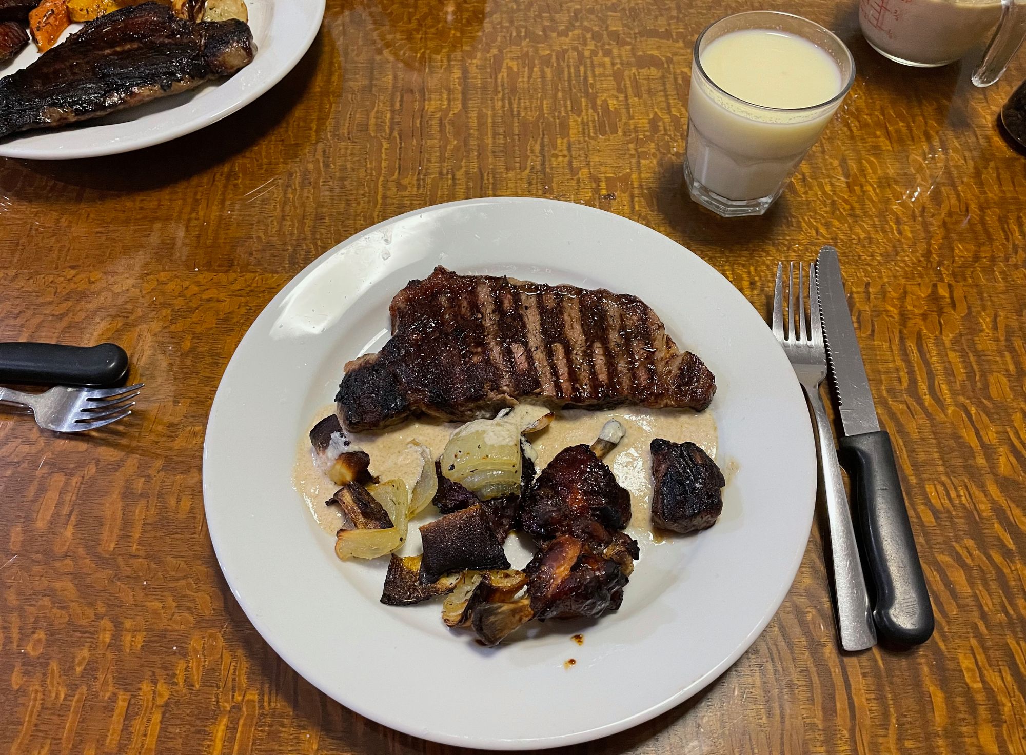 steak and onions on a plate with a glass of milk to the upper right