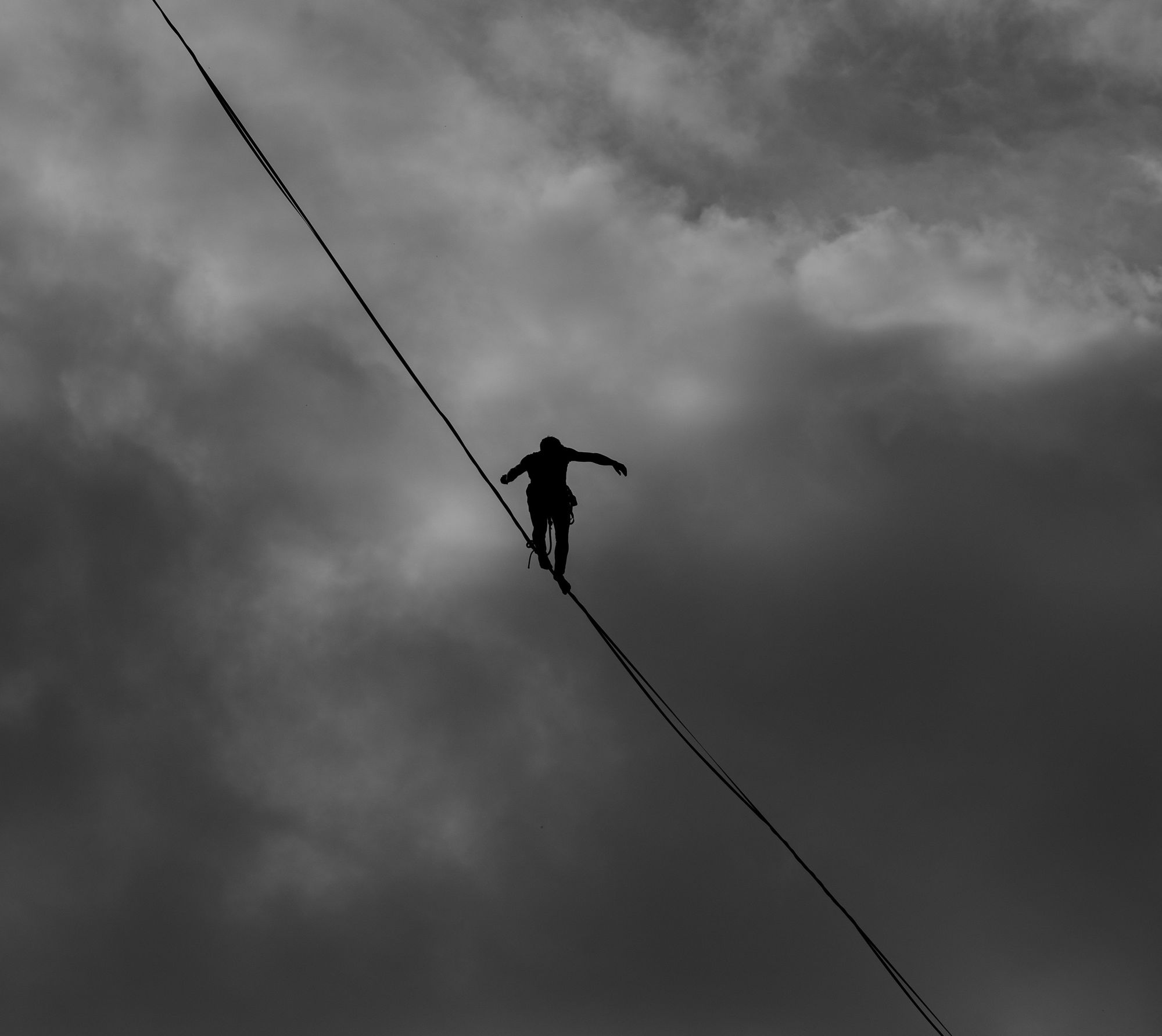 Black and white photo of tightrope walker in the sky