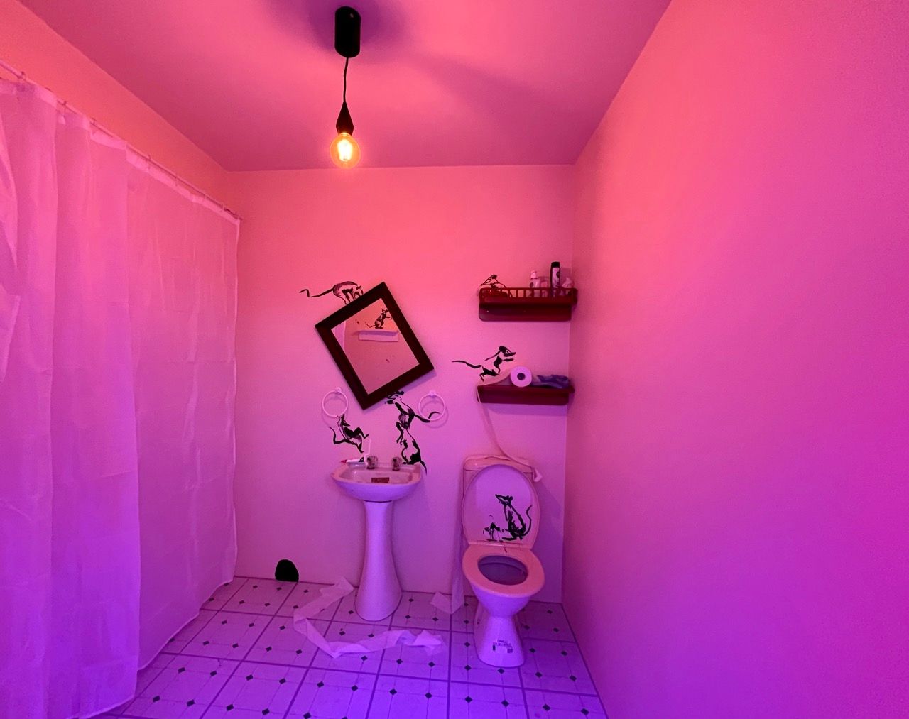 A bathroom with a pink hue to it, with mice crawling around the sink and the toilet
