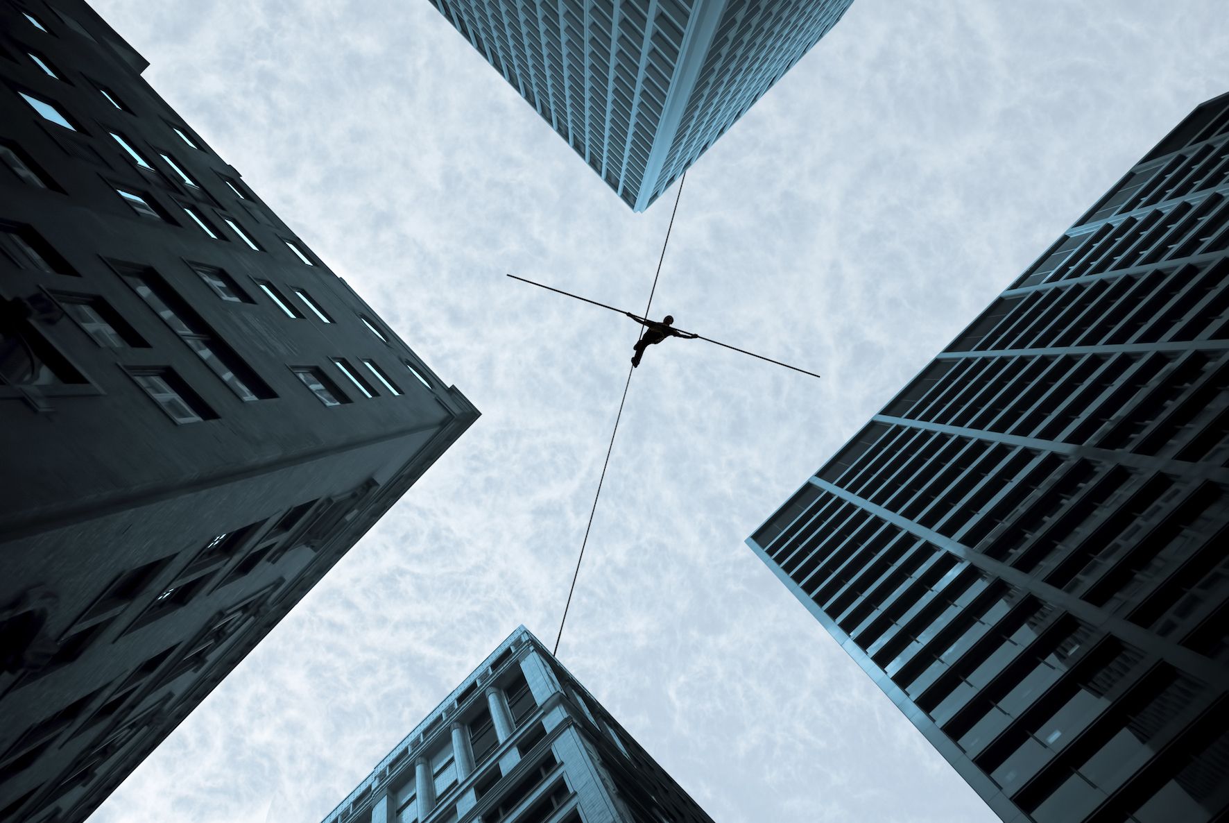 person walking tight rope between buildings