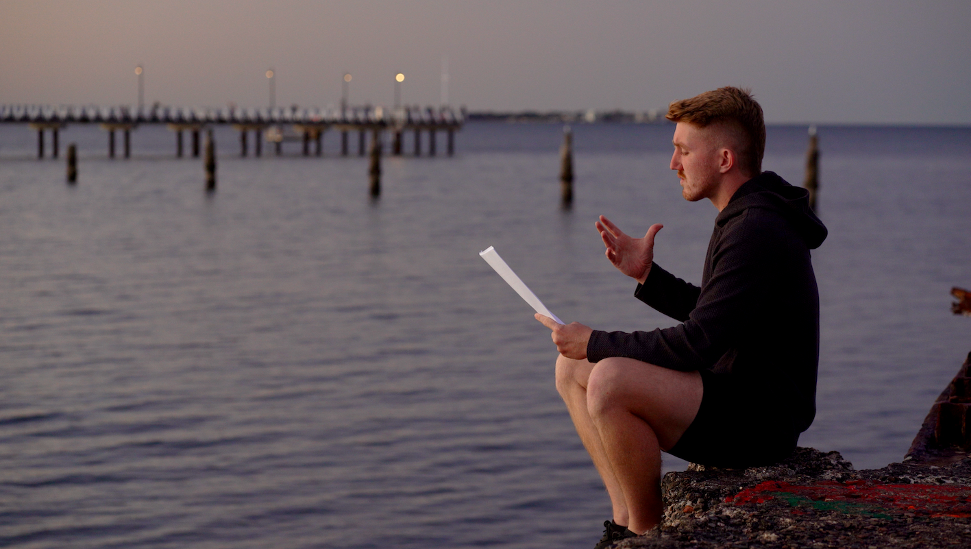 Daniel Bourke reading an excerpt of Charlie Walks on the end of a rock pier by the water