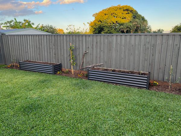 photo of a garden next to a yard with a fence behind it
